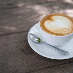 A close-up of a creamy latte with heart latte art on a wooden table, perfect for morning caffeine lovers.