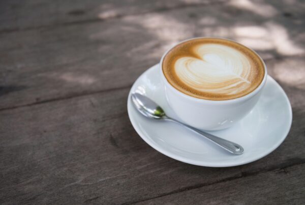 A close-up of a creamy latte with heart latte art on a wooden table, perfect for morning caffeine lovers.