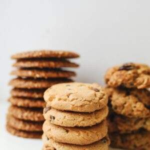 A variety of delicious homemade cookies stacked neatly in piles on a white background.