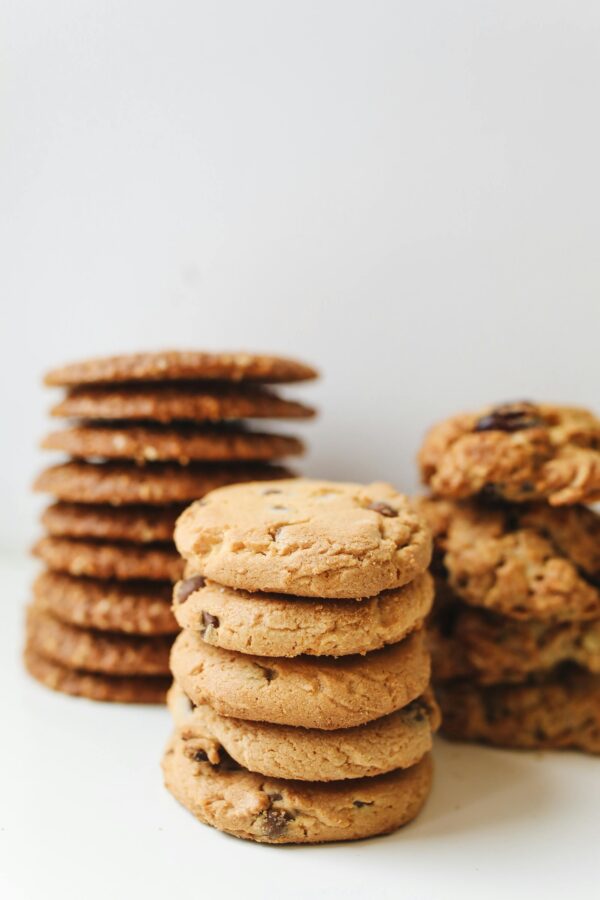 A variety of delicious homemade cookies stacked neatly in piles on a white background.